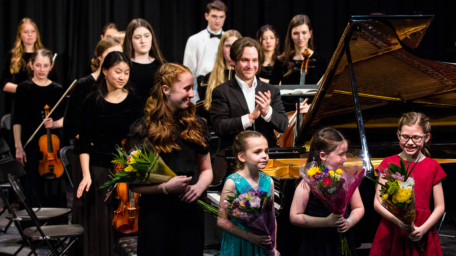Young girl pianists holding bouquets in front of the Gifted Music School Conservatory